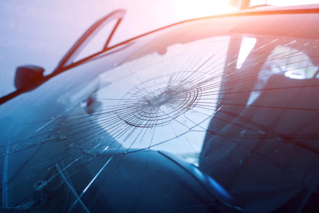 Automobile special workers remove old windscreen or windshield of a car in auto service station garage. Background