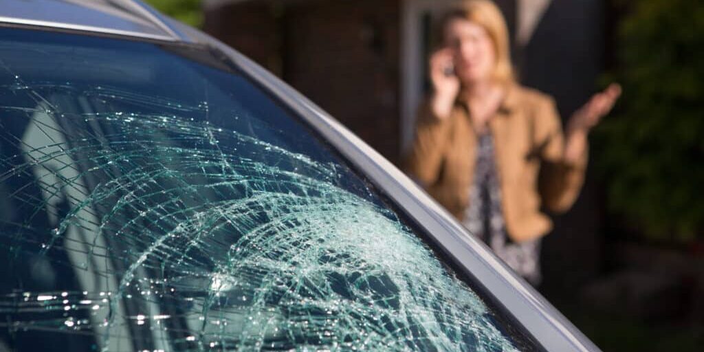 Woman Phoning For Help After Car Windshield Has Broken